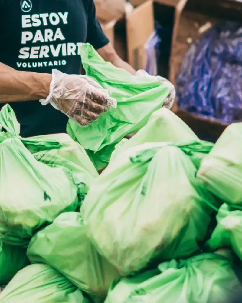 Volunteer sorting green bags of supplies, highlighting specialized IT services for non-profit organizations and charity work.